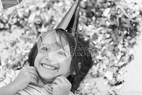 Image of kid blowing confetti while lying on the floor