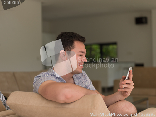 Image of young man using a mobile phone  at home