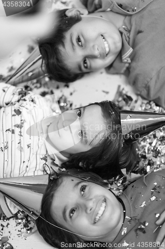 Image of kids  blowing confetti while lying on the floor