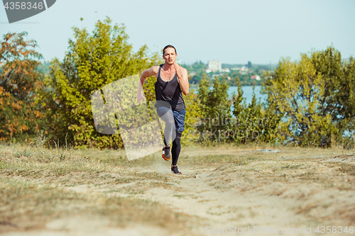 Image of Running sport. Man runner sprinting outdoor in scenic nature. Fit muscular male athlete training trail running for marathon run.