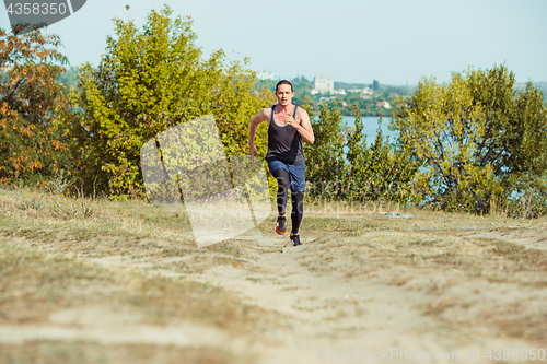 Image of Running sport. Man runner sprinting outdoor in scenic nature. Fit muscular male athlete training trail running for marathon run.