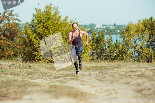 Image of Running sport. Man runner sprinting outdoor in scenic nature. Fit muscular male athlete training trail running for marathon run.