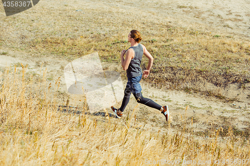 Image of Running sport. Man runner sprinting outdoor in scenic nature. Fit muscular male athlete training trail running for marathon run.