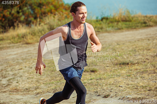 Image of Running sport. Man runner sprinting outdoor in scenic nature. Fit muscular male athlete training trail running for marathon run.