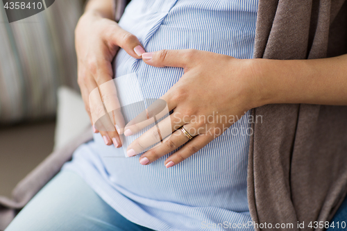 Image of close up of pregnant woman making heart on belly