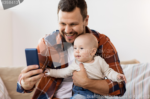 Image of happy father with baby boy taking selfie at home