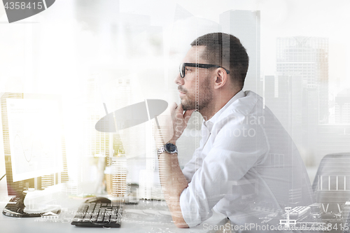 Image of businessman in glasses sitting at office computer