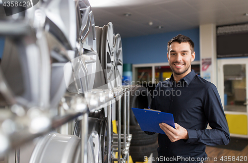 Image of auto business owner and wheel rims at car service