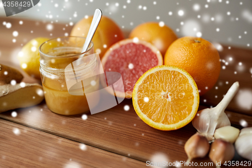 Image of honey, citrus fruits, ginger and garlic on wood