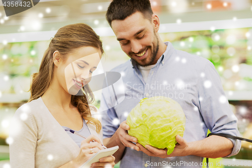 Image of couple with notebook and cabbage at grocery store