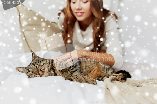 Image of young woman with cat lying in bed at home