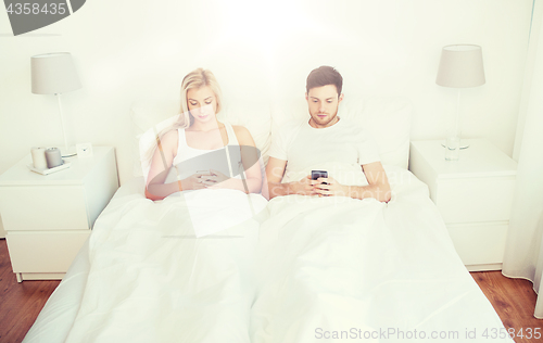 Image of couple with smartphones in bed