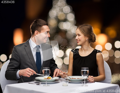Image of smiling couple eating at christmas restaurant