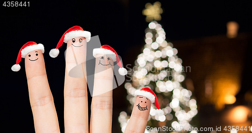 Image of close up of fingers in santa hats at christmas