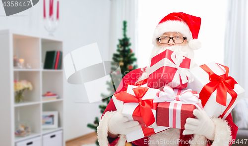 Image of santa claus with christmas gifts at home