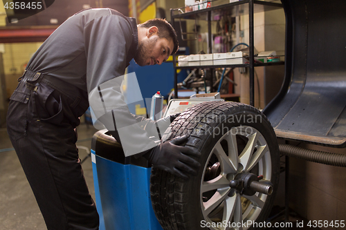 Image of auto mechanic balancing car tire at workshop