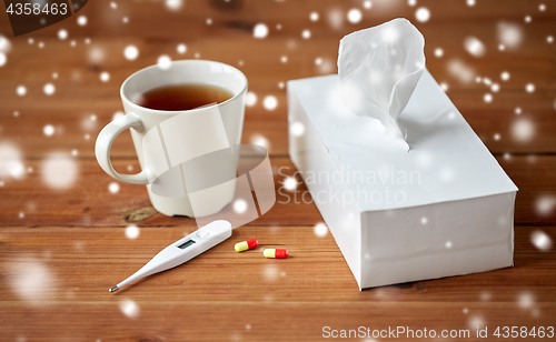 Image of cup of tea, paper wipes and thermometer with pills