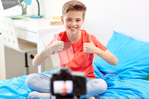 Image of happy boy with camera recording video at home