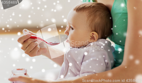 Image of close up of mother with spoon feeding little baby