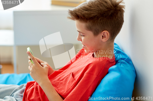 Image of happy smiling boy with smartphone at home