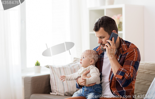 Image of father with baby calling on smartphone at home