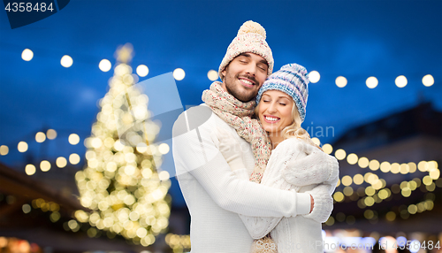 Image of happy couple hugging over christmas tree lights