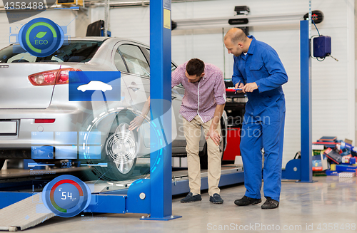 Image of auto mechanic with clipboard and man at car shop