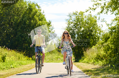 Image of happy young couple riding bicycles in summer