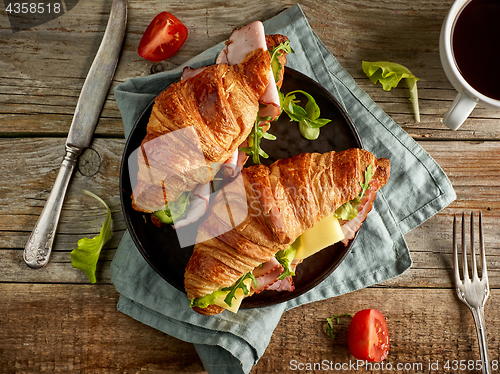 Image of two croissant sandwiches on wooden table