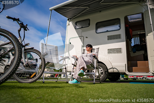 Image of Woman resting near motorhomes in nature. Family vacation travel,