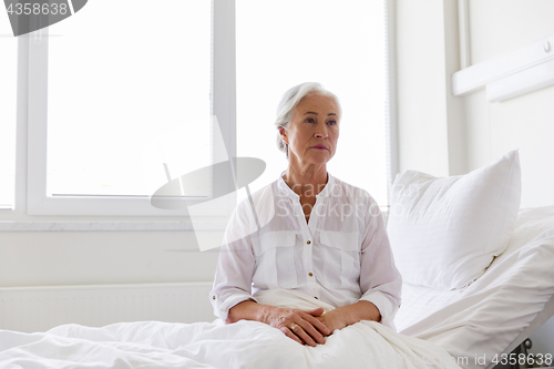 Image of sad senior woman sitting on bed at hospital ward