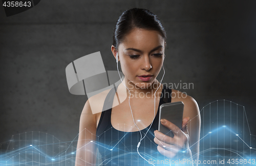 Image of woman with smartphone and earphones in gym