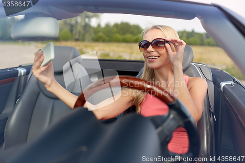 Image of woman in convertible car taking selfie