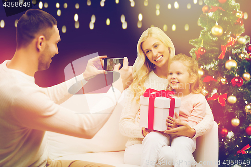 Image of man photographing his family with christmas gift