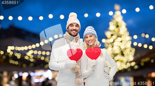 Image of couple with red hearts over christmas tree lights