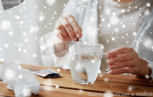 Image of ill woman stirring medication in cup with spoon