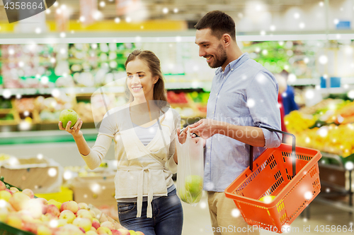 Image of happy couple buying apples at grocery store