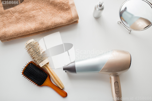 Image of hairdryer, hair brushes, mirror and towel