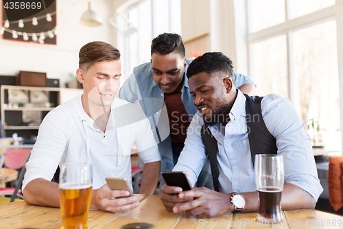 Image of male friends with smartphone drinking beer at bar