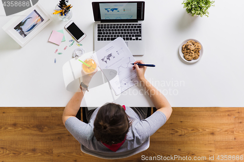 Image of woman with laptop and papers at office table