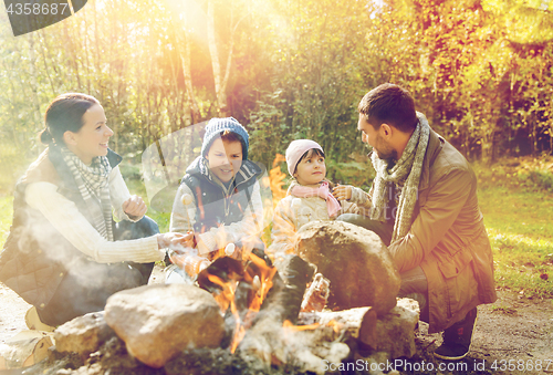 Image of happy family roasting marshmallow over campfire