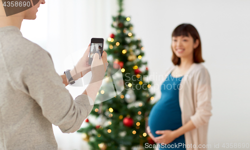 Image of husband photographing pregnant fife at christmas