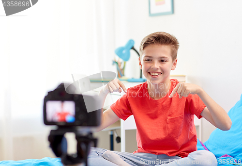 Image of happy boy with camera recording video at home