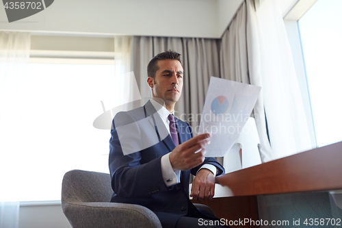 Image of businessman with papers working at hotel room