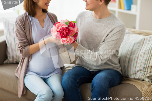 Image of close up of man giving flowers to pregnant wife