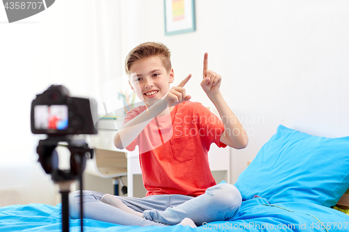 Image of happy boy with camera recording video at home