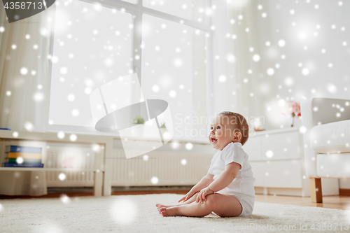 Image of happy baby boy or girl sitting on floor at home