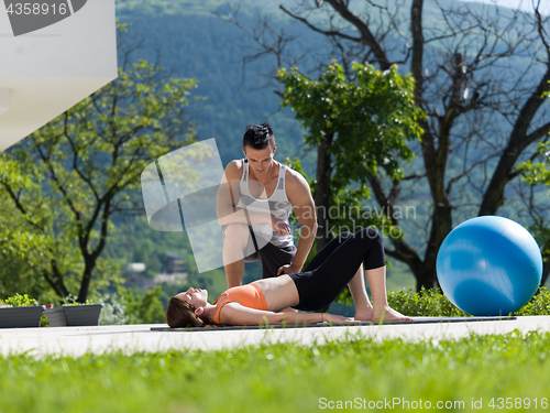 Image of woman with personal trainer doing morning yoga exercises