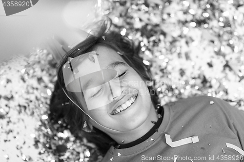 Image of kid blowing confetti while lying on the floor