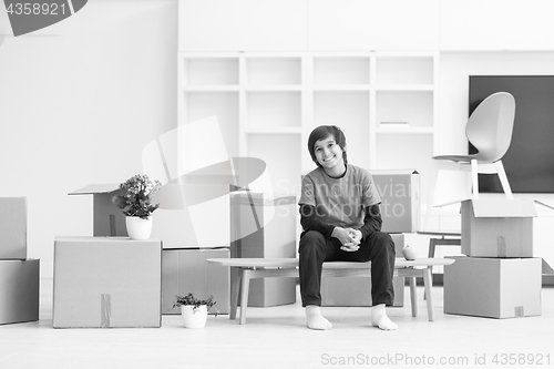 Image of boy sitting on the table with cardboard boxes around him